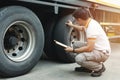 Asian a truck driver holding clipboard daily checking safety a truck wheels and tires. Royalty Free Stock Photo