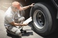 Asian a truck driver holding clipboard his checking safety a truck wheels and tires. semi truck transportation. Royalty Free Stock Photo