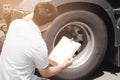 Asian a truck driver holding clipboard inspecting safety check a truck wheels and tires. Royalty Free Stock Photo