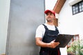 Asian truck driver wearing red cap holding a clipboard, checking the delivery packages checklists or paperwork and standing. Royalty Free Stock Photo