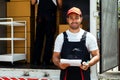 Asian truck driver wearing red cap holding a clipboard, checking the delivery packages checklists or paperwork and standing. Royalty Free Stock Photo