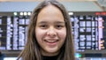 Asian tween girl in front of airport arrivals board Royalty Free Stock Photo