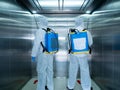 Asian two cleaner men use sanitizing spray for protect covid-19 or coronavirus and bacteria inside elevator or lift from backpack Royalty Free Stock Photo
