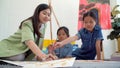 Asian two siblings learning study watercolor paint together at home. Teacher or parent teach student or daughter drawing paint