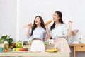 Asian two women wearing sportswear eat healthy foods in kitchen. Young beautiful girl happy and enjoy eating fruits healthy Royalty Free Stock Photo
