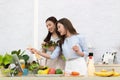 Asian two women wearing sportswear eat healthy foods in kitchen. Young beautiful girl happy and enjoy eating fruits healthy Royalty Free Stock Photo