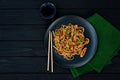 Asian udon noodles with chicken vegetables and teriyaki sauce on a black wooden background. Chinese and Japanese cuisine. Copy Royalty Free Stock Photo
