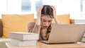 Asian upset unhappy stressed frowning face young female college student sitting working studying learning via laptop computer and Royalty Free Stock Photo