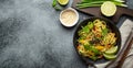 Asian vegetarian noodles with vegetables and lime in black rustic ceramic bowl, wooden chopsticks, cutting board with Royalty Free Stock Photo