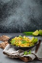 Asian vegetarian noodles with vegetables and lime in black rustic ceramic bowl, wooden chopsticks on cutting board angle Royalty Free Stock Photo