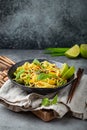 Asian vegetarian noodles with vegetables and lime in black rustic ceramic bowl, wooden chopsticks on cutting board angle Royalty Free Stock Photo