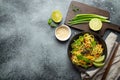 Asian vegetarian noodles with vegetables and lime in black rustic ceramic bowl, wooden chopsticks, cutting board with Royalty Free Stock Photo