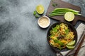 Asian vegetarian noodles with vegetables and lime in black rustic ceramic bowl, wooden chopsticks, cutting board with Royalty Free Stock Photo