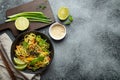 Asian vegetarian noodles with vegetables and lime in black rustic ceramic bowl, wooden chopsticks, cutting board with Royalty Free Stock Photo