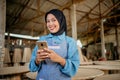 asian veiled businesswoman using a smartphone in a woodcraft shop