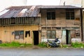 Asian village. An old wooden house near which a modern motorcycle stands. Clothes are drying on a rope nearby
