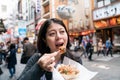 asian visitor eating takoyaki happily. a kind of japanese cuisine
