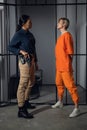 Asian warden and a female prisoner in a high-security prison stand in front of an open cell.