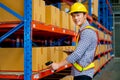 Asian warehouse worker hold barcode scaner and tablet and look at camera with smiling