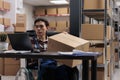 Asian wheelchair user managing parcel delivery in postal warehouse