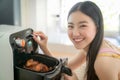 Asian wife cooking fries chicken by use her electric fryer in her kitchen