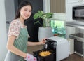 Asian wife cooking fries chicken by use her electric fryer in her kitchen at home Royalty Free Stock Photo