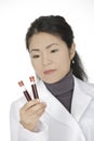 Asian woman laboratory technician examining a tube of blood