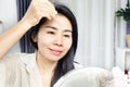 Asian woman age 40s applying serum collagen on her skin face, forehead for anti-aging and winkles