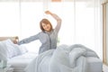 An Asian woman aged about 20 wakes up in the morning in a bright bed in a bedroom or hotel After a restful night`s sleep