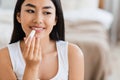 Asian woman applying hygienic lip balm at home