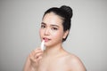 Asian woman applying hygienic lip balm over grey background Royalty Free Stock Photo