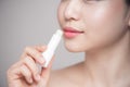 Asian woman applying hygienic lip balm over grey background Royalty Free Stock Photo