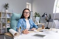 Asian woman architect in glasses working at a desk at a computer and drawing on a project Royalty Free Stock Photo