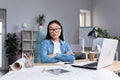 Asian woman architect in glasses working at a desk at a computer and drawing on a project Royalty Free Stock Photo