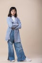 a young asian woman is posing with her arms crossed wearing a shirt, jeans, Royalty Free Stock Photo