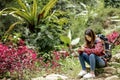 Asian woman with a backpack sitting on a rock using a mobile phone Royalty Free Stock Photo
