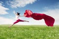 Asian woman ballerina holding red fabric making a big jump on blossom meadow. Royalty Free Stock Photo