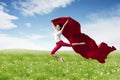 Asian woman ballerina holding red fabric making a big jump on blossom meadow. Royalty Free Stock Photo