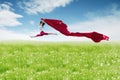 Asian woman ballerina holding red fabric making a big jump on blossom meadow. Royalty Free Stock Photo