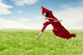 Asian woman ballerina holding red fabric making a big jump on blossom meadow. Royalty Free Stock Photo