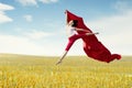 Asian woman ballerina holding red fabric making a big jump on meadow. Royalty Free Stock Photo