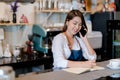 Asian woman Barista calling with customer at front counter occupation, part-time Royalty Free Stock Photo