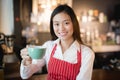 Asian woman barista smiling with a cup of coffee in her hand,Coffee salesmen deliver coffee to customers,vintage filter effect Royalty Free Stock Photo