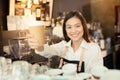 Asian woman barista smiling with a cup of coffee in her hand Royalty Free Stock Photo