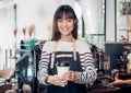 Asian woman barista wear jean apron holding hot take away coffee Royalty Free Stock Photo