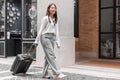 Asian woman beaming carrying a suitcase black to travel on vacation