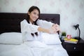 Asian woman Beautiful young smiling woman sitting on bed and stretching in the morning at bedroom after waking up in her bed fully Royalty Free Stock Photo