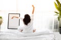 Asian woman Beautiful young smiling woman sitting on bed and stretching in the morning at bedroom after waking up in her bed full Royalty Free Stock Photo