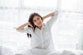 Asian woman Beautiful young smiling woman sitting and sleeping in white bed and stretching in the morning at bedroom after waking Royalty Free Stock Photo