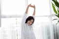 Asian woman Beautiful young smiling woman sitting on bed and stretching in the morning at bedroom after waking up in her bed full Royalty Free Stock Photo